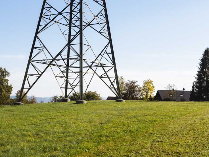Mast einer Stromleitung auf einer Wiese
