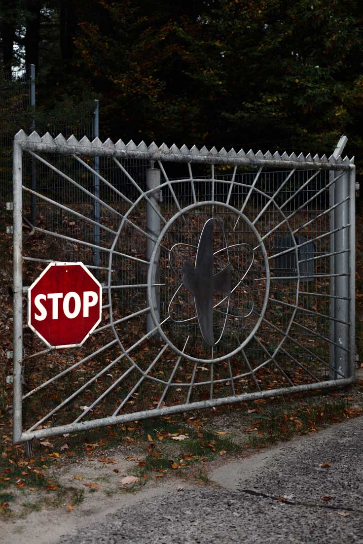 Gittertor mit strahlender Friedenstaube in der Mitte, an dem ein Stopp-Schild hängt